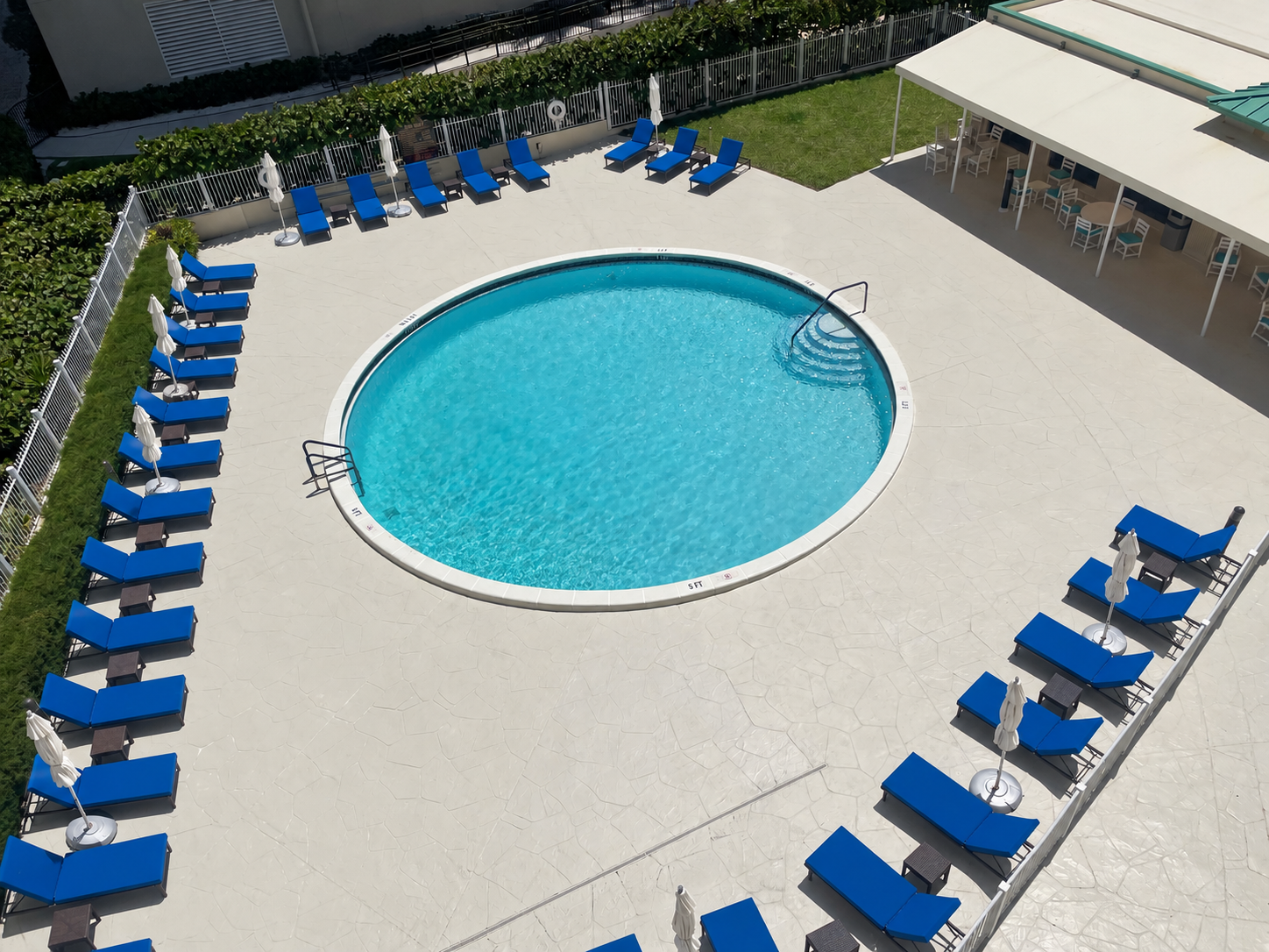 The building's pool deck seen from above, with loungers and a covered terrace